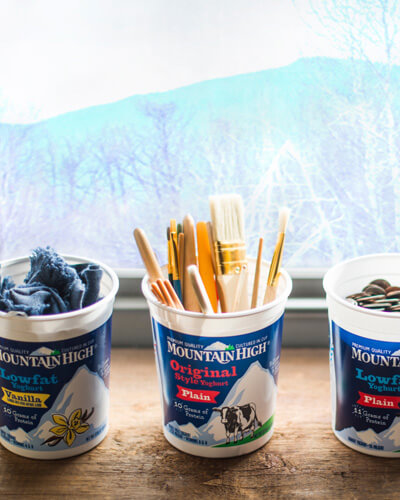 Empty tubs of Mountain High Yoghurt filled with pencils and fabric scraps