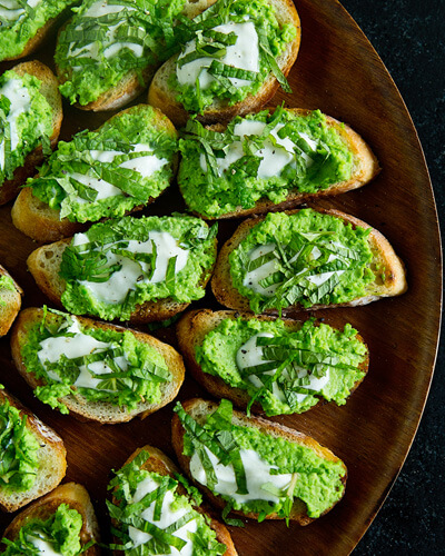 plate of crostini topped with pea puree and yoghurt