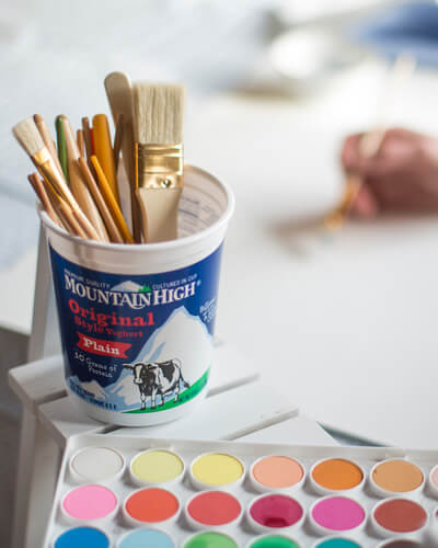 paint brushes in a yoghurt tub
